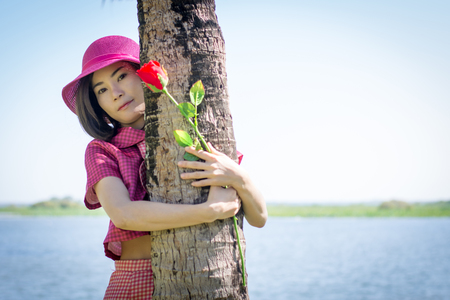 Happy young woman with holding roses in the coconut park.の写真素材