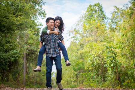 Close up Young girl riding a young man on a forest road.の写真素材