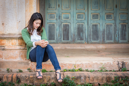 Depressed women. Asian beautiful girl sits sadly on the cement floor in ancient houses.の写真素材