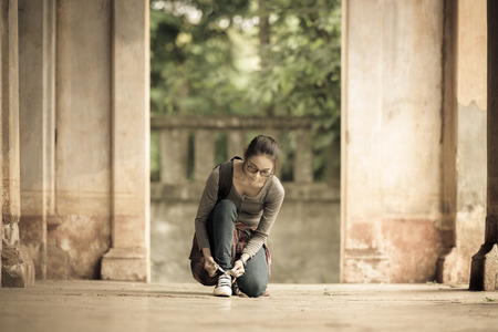 Asian young woman is tying a shoelace in an ancient building.の写真素材