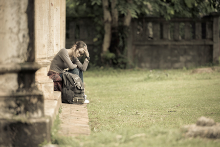 Depressed women. Asian beautiful girl sits sadly on the cement floor in ancient houses. Vintage tone.の写真素材