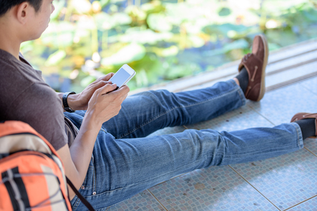 Hipster men playing games on the phone near the river.の写真素材