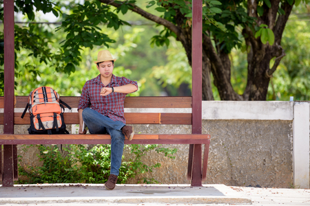 Bus stop with backpackers are watching the clock while waiting for the bus to travel.の写真素材
