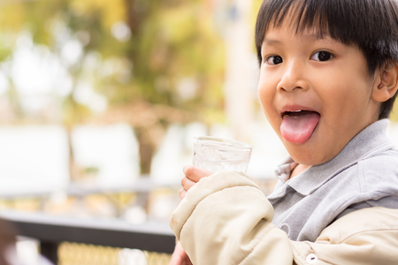 Boy is drinking water sitting in a cafe.の写真素材