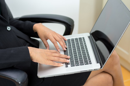 Businesswoman sitting on a laptop sitting on a chair 