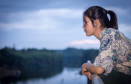 Portrait of a beautiful young woman standing by the river at dusk.の写真素材