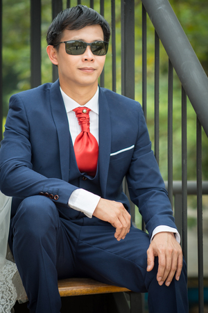 Man wearing a wedding dress and with the glasses sitting on the stairs to enjoy.の写真素材
