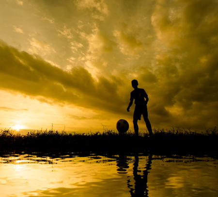 Silhouette Athletes playing football while the sun sets.の写真素材