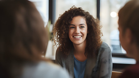 A young woman with curly hair is smiling and looking at someone while having a conversation.の素材