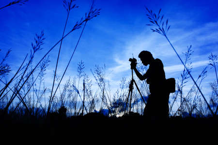 Silhouette of the photographer on a Grass on a foreground of cloudsの写真素材