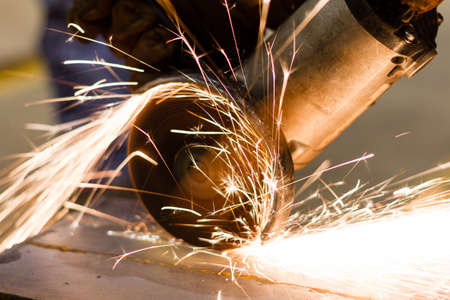 Worker cutting metal with many sharp sparks