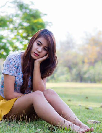 Depressed young woman sitting alone in gardenの写真素材