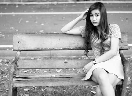 Depressed young woman sitting alone in gardenの写真素材