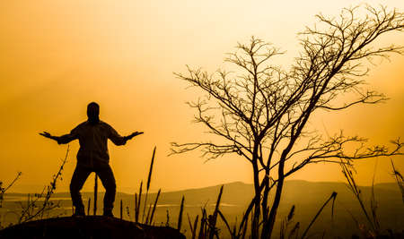 praying man silhouette on sunset backgroundの写真素材