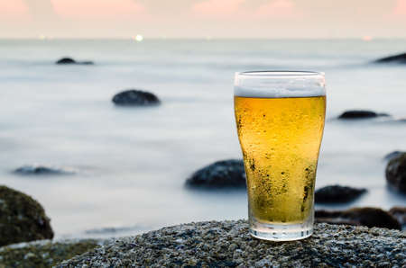 A glass of beer with sea backgroundの写真素材