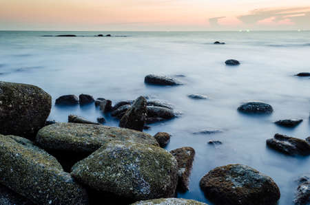 Wave and the rock with sunset skyの写真素材