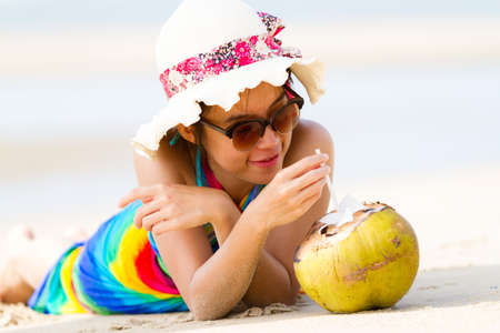 Young woman in  with coconut cocktail on the beachの写真素材