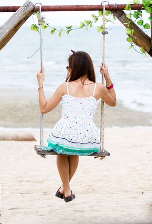 Beautiful woman in a  dress on a swing の写真素材