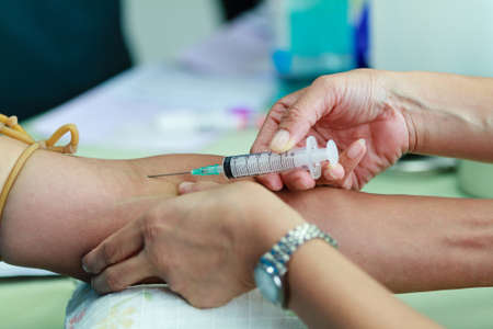 Doctor drawing blood sample from arm for blood test の写真素材
