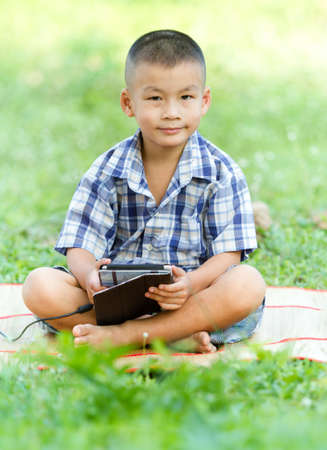 Boy holding tablet PC in gardenの写真素材