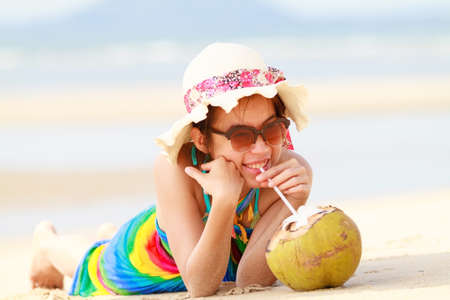 Young woman in swimsuit with coconut cocktail on the beach, Thailandの写真素材