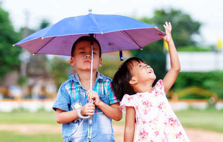 Brother and a sister with umbrella in the parkの写真素材