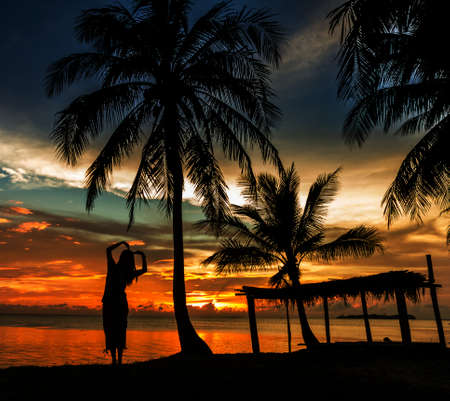 Woman with coconut palm in silluate backgroundの写真素材