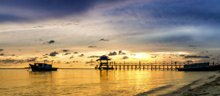 Sunset over the sea. Pier on the foreground 