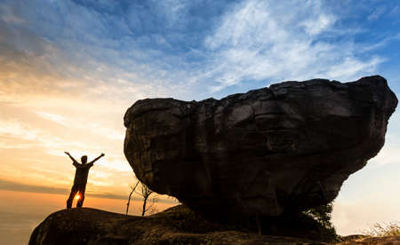 Man on top of mountain with big rock