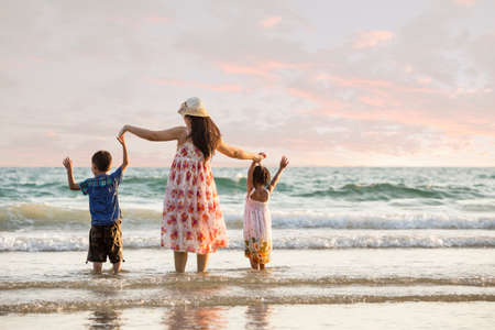 Happy family standing on the beach on the dawn time の写真素材