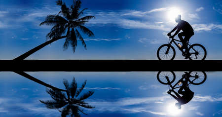 silhouette of cyclist in motion on the background of a beautiful blue sky の写真素材