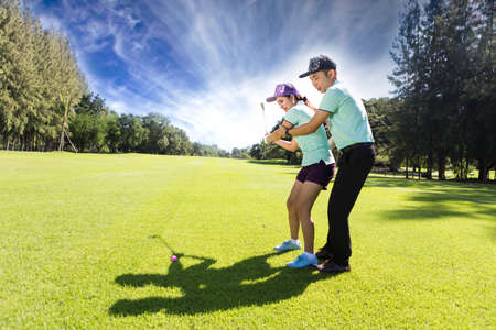 Young female golf player at Driving Range with a Golf Pro, she presumably does exerciseの写真素材