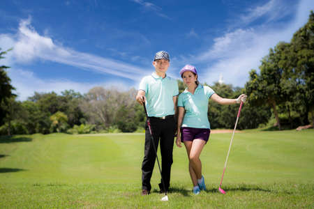 Young sportive couple playing golf on a golf course, they certainly do exercise or have trainingの写真素材