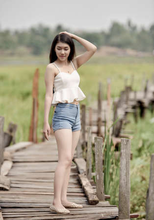 Pretty young asian woman walking on wood bridgeの写真素材