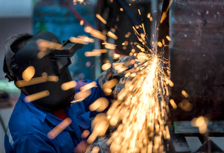Electric wheel grinding on steel pipe in factoryの写真素材
