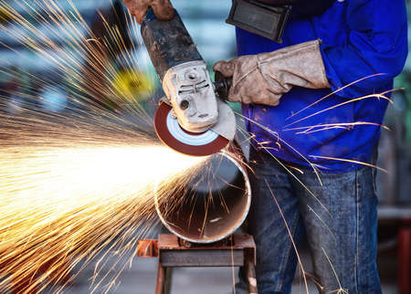Electric wheel grinding on steel pipe in factoryの写真素材