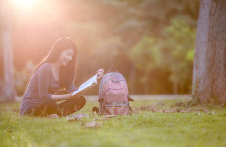 Portrait of happy charming Thai woman reading a book outdoors