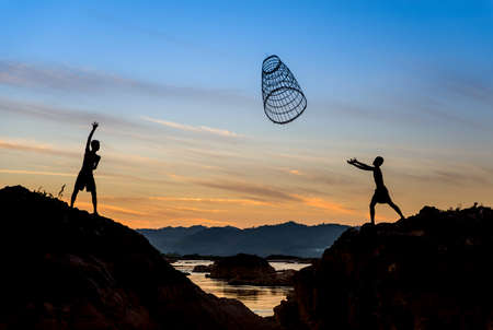 Children sharing tool for fishing In the Sunset.の写真素材