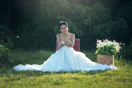 Portrait of beautiful bride sitting on the chair outdoorsの写真素材
