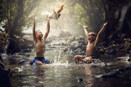 Boys playing with their duck in the creekの写真素材