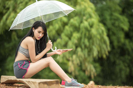 Woman sitting lonely with umbrella. Concept of taking a breakの写真素材