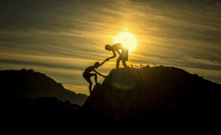 Silhouette of helping hand between two boys climberの写真素材