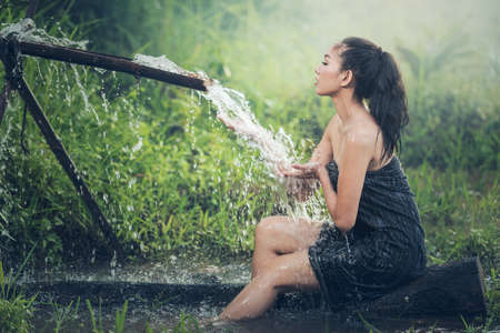 Beautiful young woman takes bath naturally flows from the bamboo chuteの写真素材
