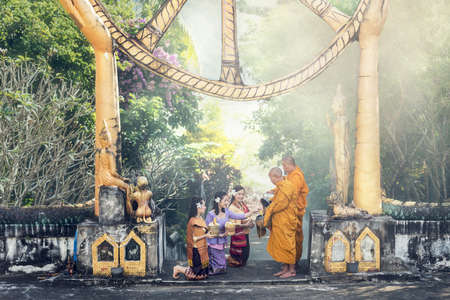 THAI COSTUME Beauty young woman donate food to the monks in the morning. Buddhist monk Baanmueng Nongkai Thailand.の写真素材
