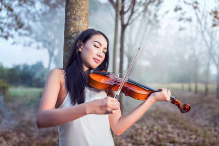Portrait of woman dress in white long dress playing the violin, soft focus and vintage toneの写真素材