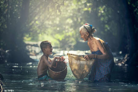 Asian Grandmother and her child are fishing in the creek at countryside of Thailandの写真素材