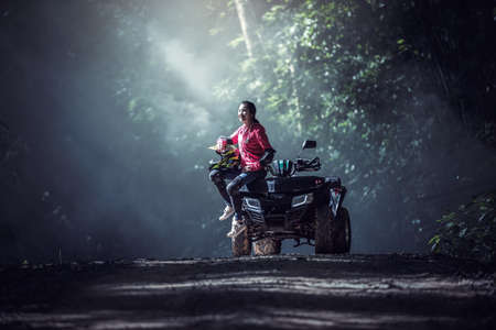 Elegant woman riding quadricycles ATV in forestの写真素材