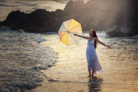 Happy Carefree Woman Enjoying Beautiful Sunset on the Beachの写真素材