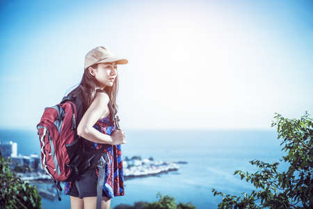 Hiker with backpack relaxing on top of a mountain and enjoying valley viewの写真素材