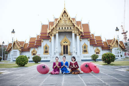 Woman tourist with red traditional Thai umbrella at Wat Benchamabophit the marble temple in Bangkok, Thailandの写真素材